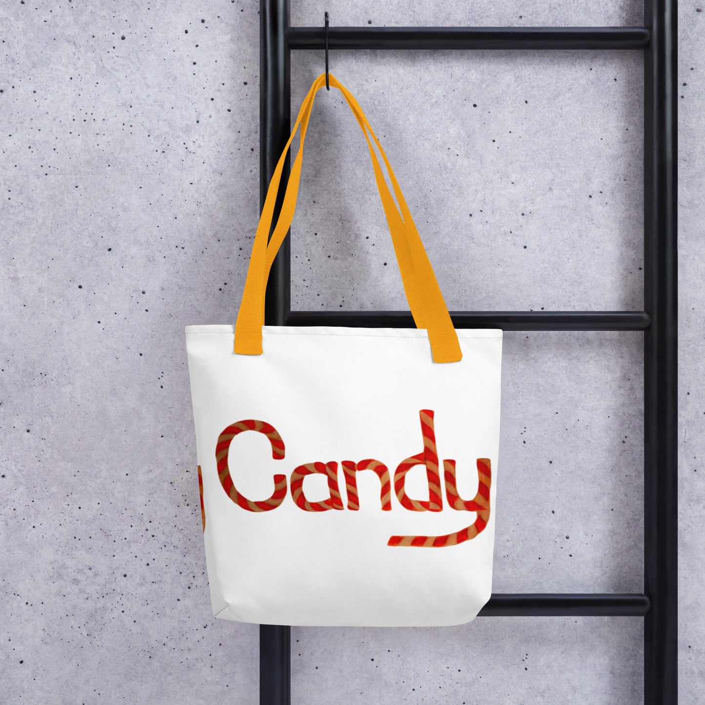 White tote bag with cute candy print and yellow handles hanging on black ladder