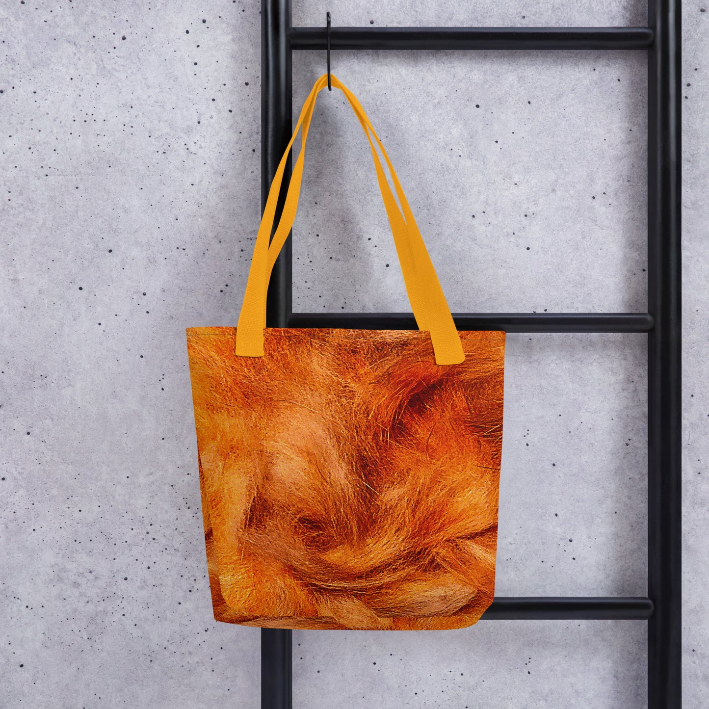 Orange textured tote bag with yellow straps hanging on black ladder everyday carry beach bag