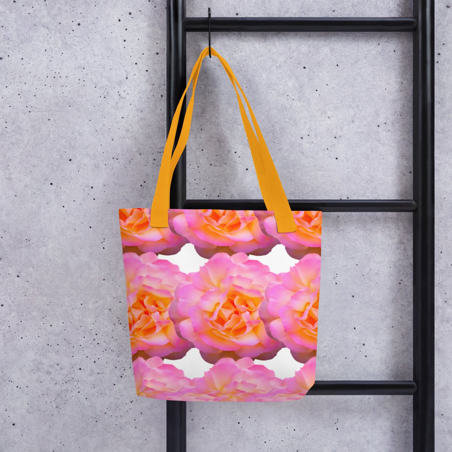 Pink rose shopper bag with vibrant floral print and yellow straps hanging on black ladder