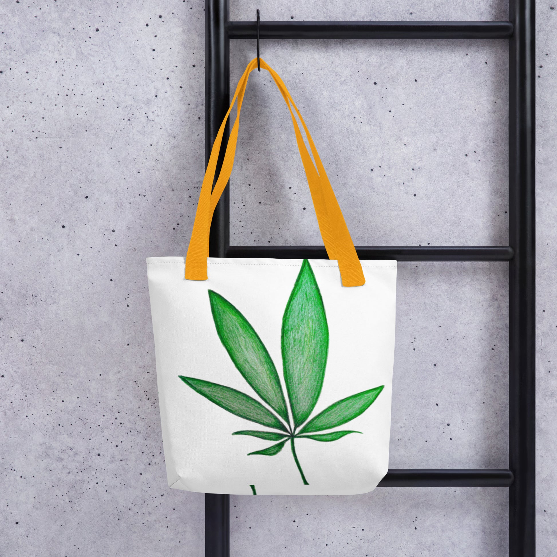 White canvas shopping tote with leaf design and yellow handles hanging on black ladder