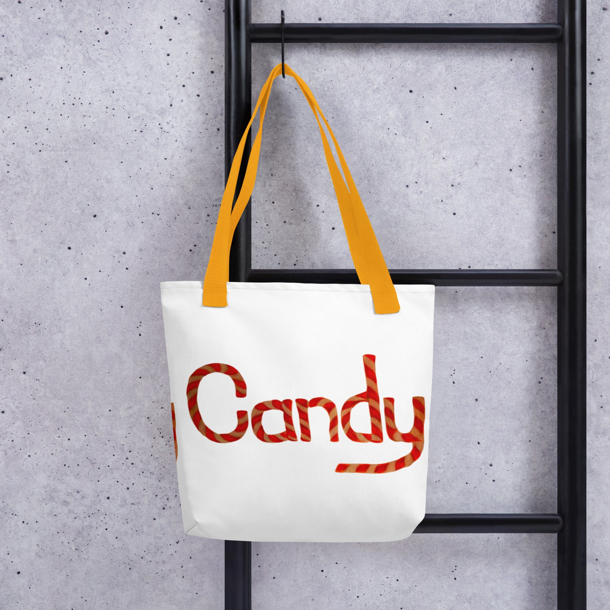 White tote bag with cute candy print and yellow handles hanging on black ladder