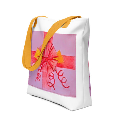 White tote bag with yellow straps featuring a pink ribbon gift tote design with a large bow and curly ribbons