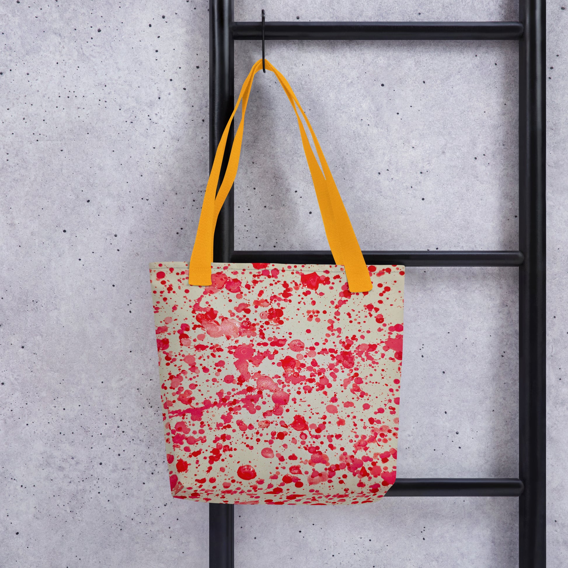 Unique designer tote bag women with red splatter pattern and bright yellow handles hanging on black ladder