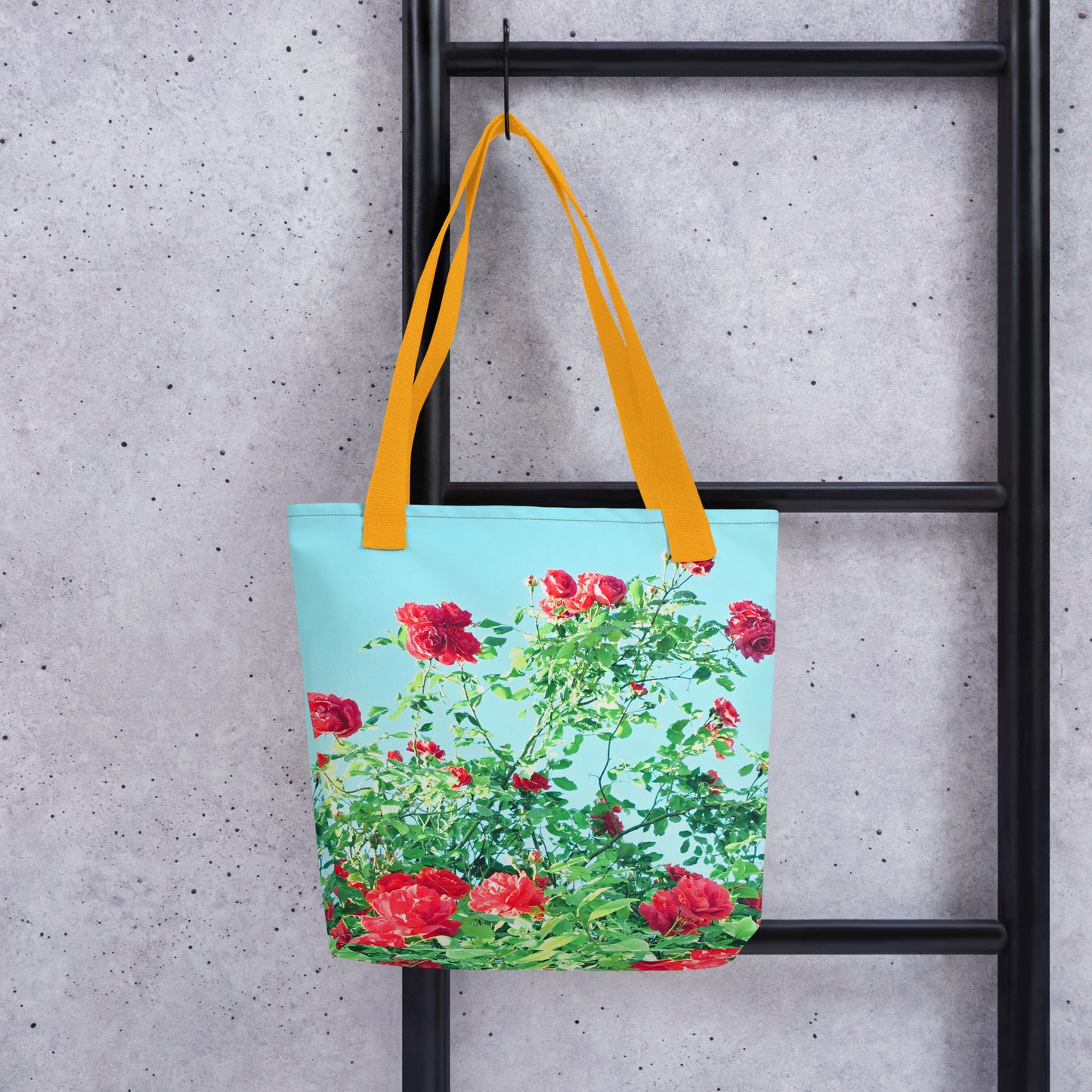 VINTAGE ROSE PRINT rose print beach tote with bright orange handles hanging on black ladder